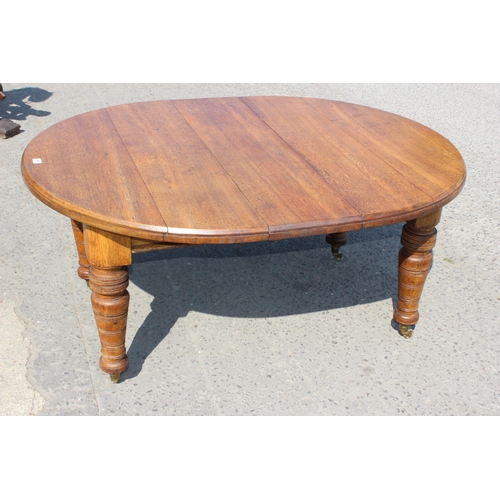 91 - An antique oak extending dining table with heavy turned legs and brass castors, 2 extra leaves, appr... 