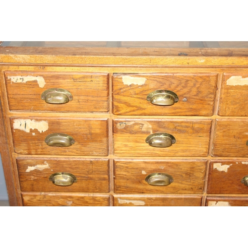 81 - An early 20th century light oak haberdashery shop counter or display cabinet with 30 drawers with br... 