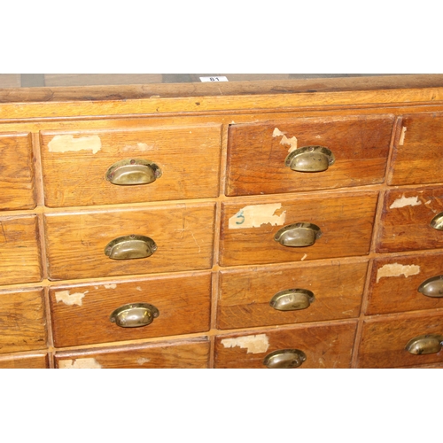 81 - An early 20th century light oak haberdashery shop counter or display cabinet with 30 drawers with br... 