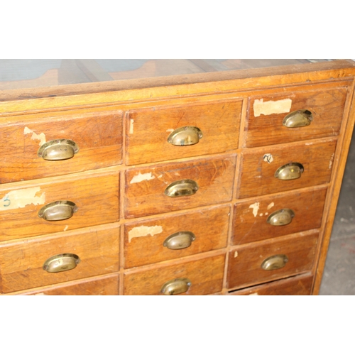 81 - An early 20th century light oak haberdashery shop counter or display cabinet with 30 drawers with br... 