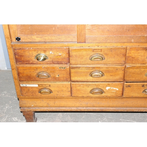 82 - An early 20th century light oak haberdashery shop counter or display cabinet with 15 drawers with br... 