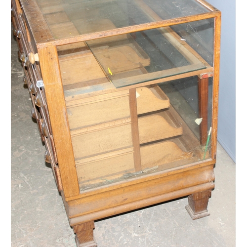 82 - An early 20th century light oak haberdashery shop counter or display cabinet with 15 drawers with br... 