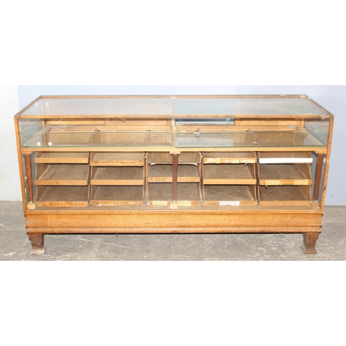 82 - An early 20th century light oak haberdashery shop counter or display cabinet with 15 drawers with br... 