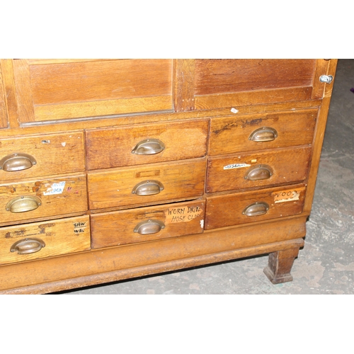 82 - An early 20th century light oak haberdashery shop counter or display cabinet with 15 drawers with br... 