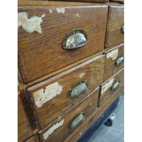 81 - An early 20th century light oak haberdashery shop counter or display cabinet with 30 drawers with br... 