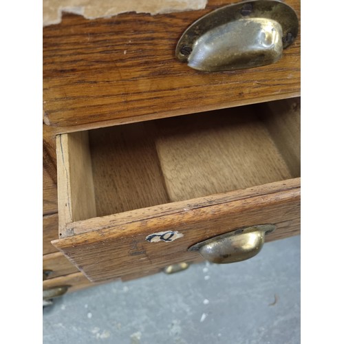 81 - An early 20th century light oak haberdashery shop counter or display cabinet with 30 drawers with br... 