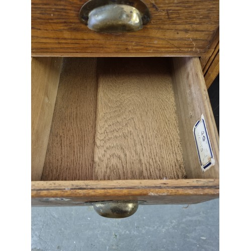 81 - An early 20th century light oak haberdashery shop counter or display cabinet with 30 drawers with br... 