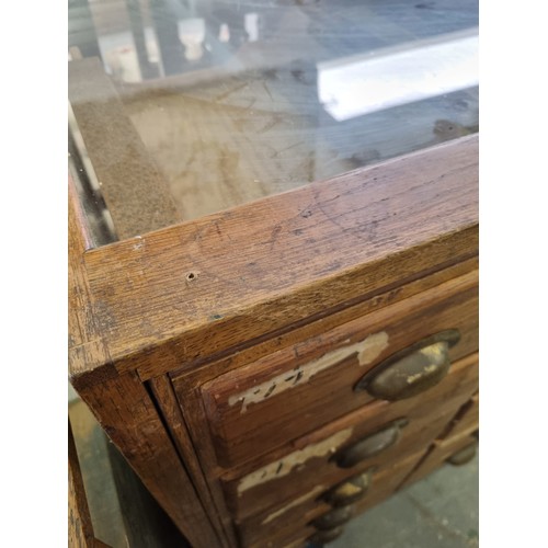 81 - An early 20th century light oak haberdashery shop counter or display cabinet with 30 drawers with br... 