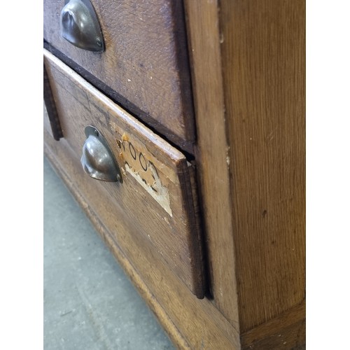 82 - An early 20th century light oak haberdashery shop counter or display cabinet with 15 drawers with br... 