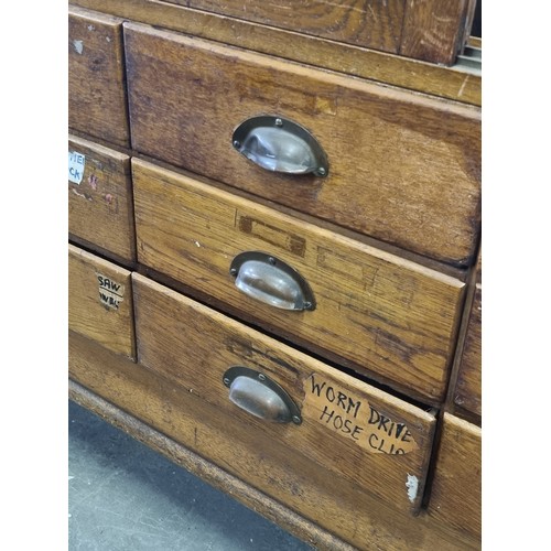 82 - An early 20th century light oak haberdashery shop counter or display cabinet with 15 drawers with br... 