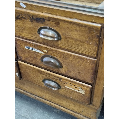 82 - An early 20th century light oak haberdashery shop counter or display cabinet with 15 drawers with br... 