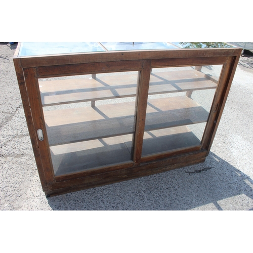 87 - A vintage shop display cabinet or counter of slanted form, approx 150cm wide x 110cm tall