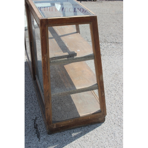 87 - A vintage shop display cabinet or counter of slanted form, approx 150cm wide x 110cm tall