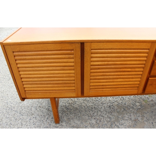 55A - A retro A.H. McIntosh of Kirkcaldy teak sideboard, with three central short drawers, the top drawer ... 