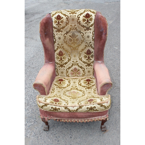 18 - A pair of antique wingback armchairs with later upholstery, short wooden legs ending in carved lion ... 