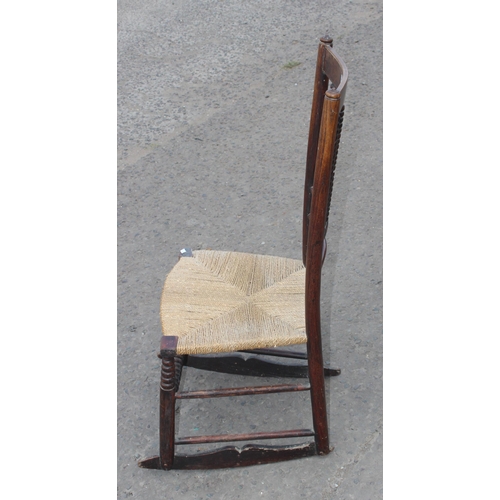 20 - An Arts & Crafts period rush seated rocking chair in the manner of Liberty, with bobbin turned stret... 