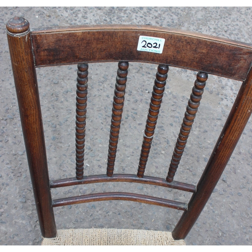 20 - An Arts & Crafts period rush seated rocking chair in the manner of Liberty, with bobbin turned stret... 