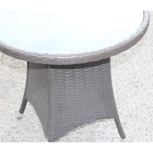 114 - Rattan and glass topped garden table, approx 70cm in diameter