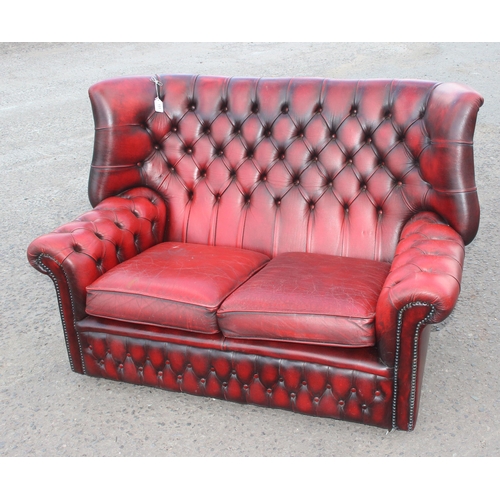 151 - An Ox-Blood red Chesterfield wing back 2 seater sofa, approx 143cm wide x 95cm deep x 96cm tall