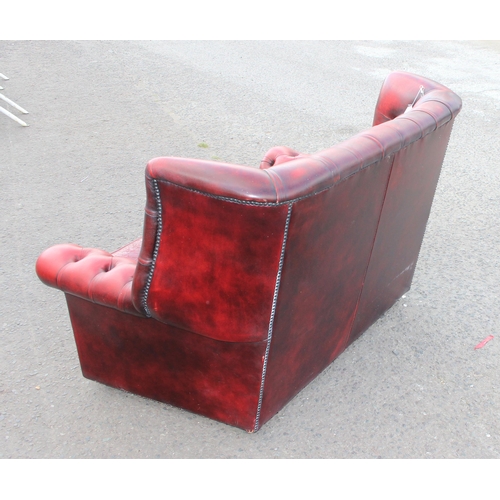 151 - An Ox-Blood red Chesterfield wing back 2 seater sofa, approx 143cm wide x 95cm deep x 96cm tall