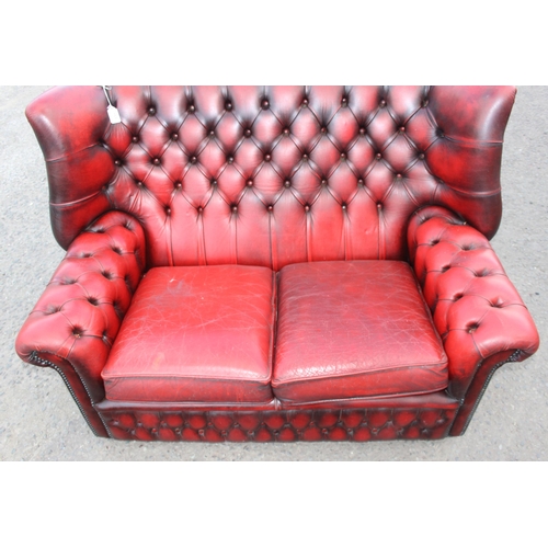 151 - An Ox-Blood red Chesterfield wing back 2 seater sofa, approx 143cm wide x 95cm deep x 96cm tall