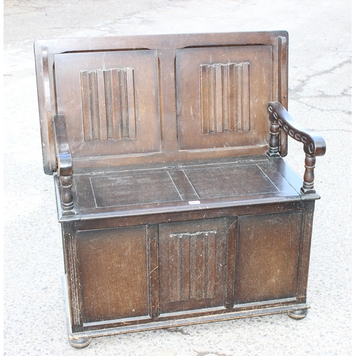 163 - A vintage oak metamorphic monk's bench, the back folding flat to become a table over a storage box s... 