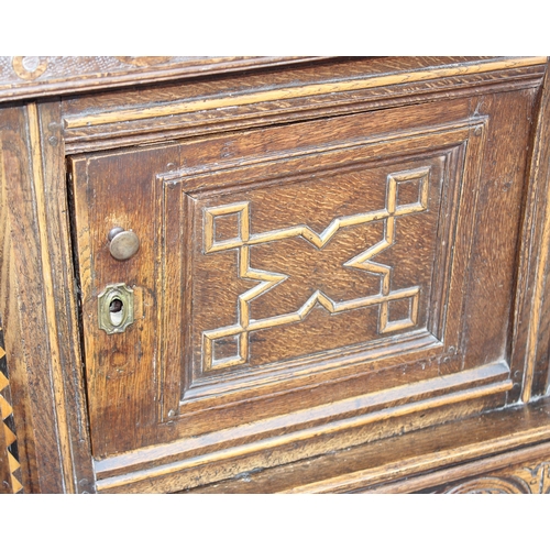 165 - An antique English oak court cupboard formed from a 17th century coffer, profusely carved and with g... 