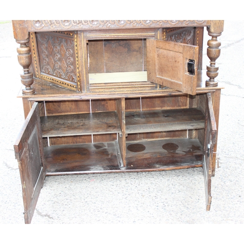 165 - An antique English oak court cupboard formed from a 17th century coffer, profusely carved and with g... 