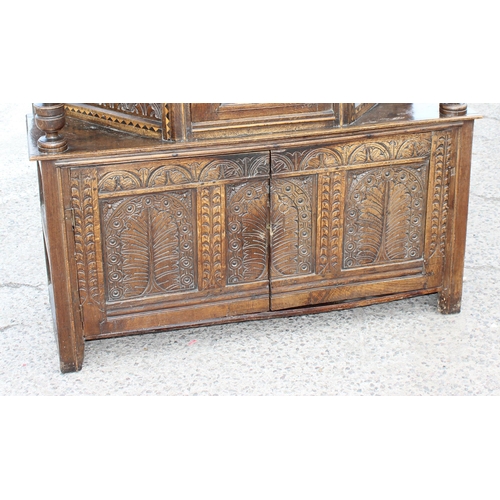 165 - An antique English oak court cupboard formed from a 17th century coffer, profusely carved and with g... 