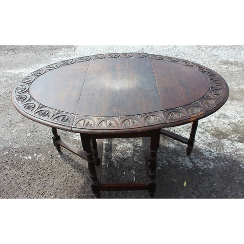 14 - An antique oak drop leaf table with carved details. approx 150cm wide x 107cm deep x 73cm tall