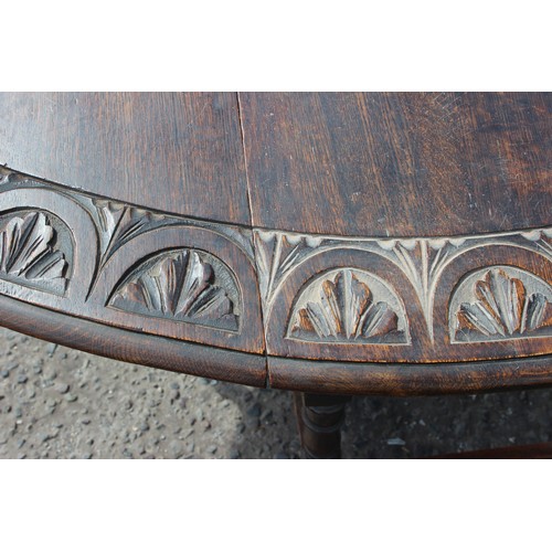 14 - An antique oak drop leaf table with carved details. approx 150cm wide x 107cm deep x 73cm tall