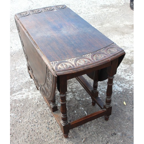 14 - An antique oak drop leaf table with carved details. approx 150cm wide x 107cm deep x 73cm tall