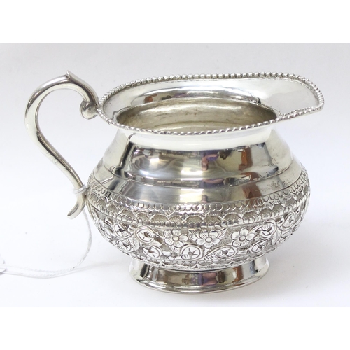 1035 - A large embossed silver cream or milk jug, likely Anglo-Indian, marked St Silver to the base and XRF... 