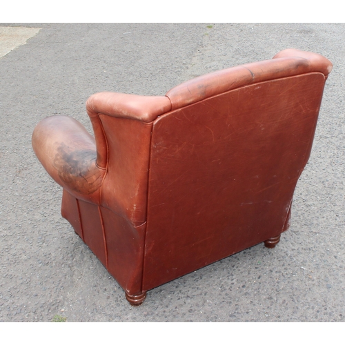 85 - A vintage brown leather club chair with turned wooden feet, approx 100cm wide