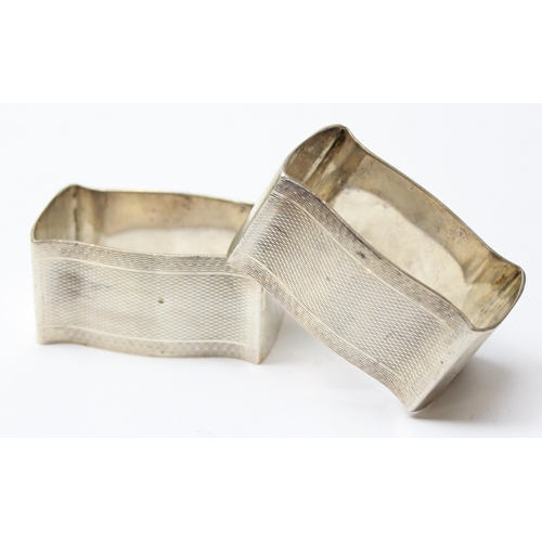 1046 - A heavy pair of silver napkin rings of cushion form, with engine turned design, Birmingham 1928 by W... 