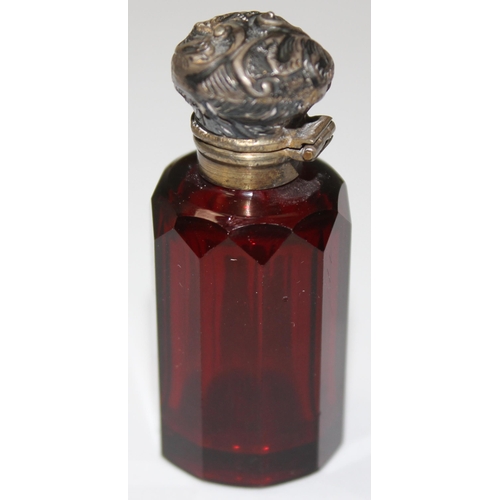 1072 - Victorian ruby glass scent bottle with a gilded top and complete with glass stopper, top seemingly u... 