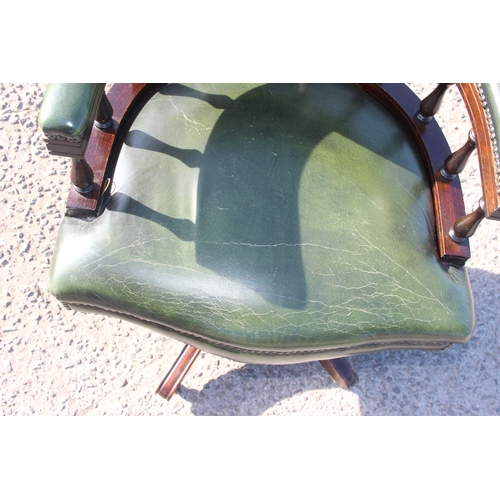 155 - A green leather captain's style desk chair with chesterfield button back