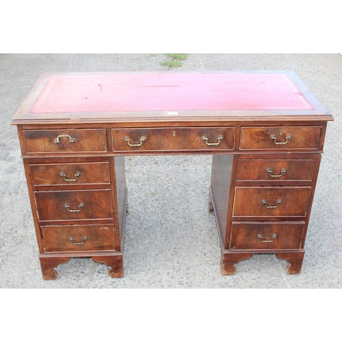 159 - A red leather topped and mahogany effect 3 part pedestal desk, approx 121cm wide x 61cm deep x 67cm ... 