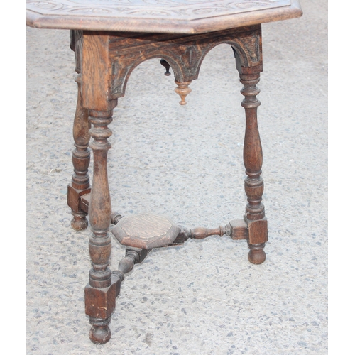 135 - An Arts & Crafts period carved oak octagonal table, the top carved with leaves and decorative demi-l... 