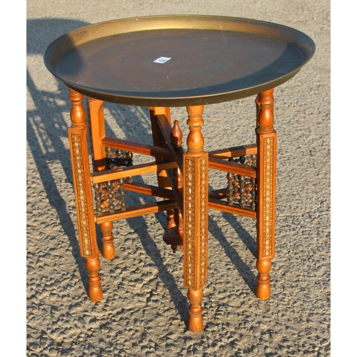 78 - A Benares brass topped tray table with folding wooden base, the top approx 56cm in diameter