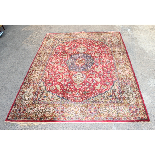 217 - A large vintage Persian Heriz style rug, red ground decorated with animals and Persian script to the... 