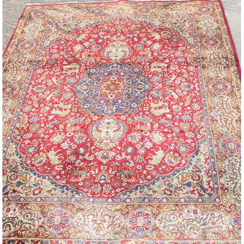 217 - A large vintage Persian Heriz style rug, red ground decorated with animals and Persian script to the... 