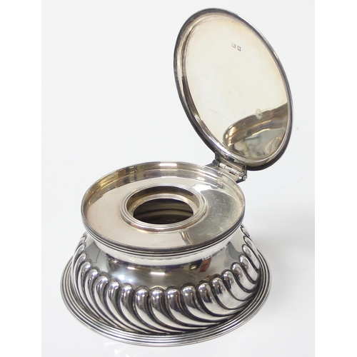 1003 - An antique silver inkwell with glass liner, the body with half gadrooned border, Birmingham 1919 by ... 