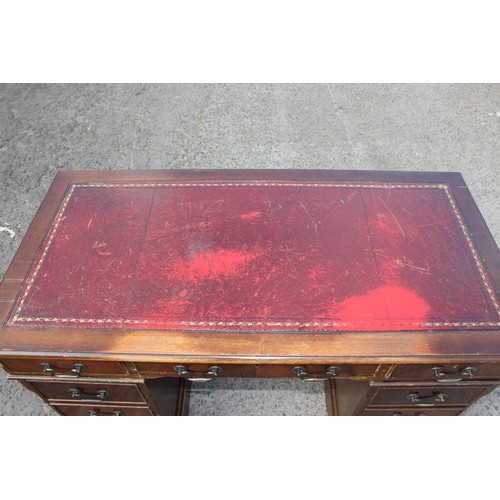 88 - A red leather topped and mahogany effect 3 part pedestal desk, approx 121cm wide x 61cm deep x 67cm ... 