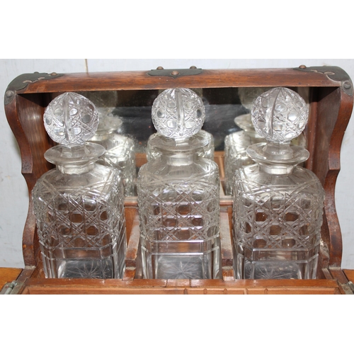 283 - Antique oak tantalus with brass fittings with 3 matching cut glass decanters and shot glasses approx... 