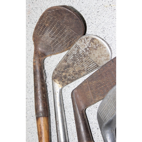 704 - Qty of vintage wooden handled and other golf clubs to include various irons and putters