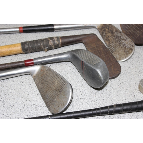 704 - Qty of vintage wooden handled and other golf clubs to include various irons and putters