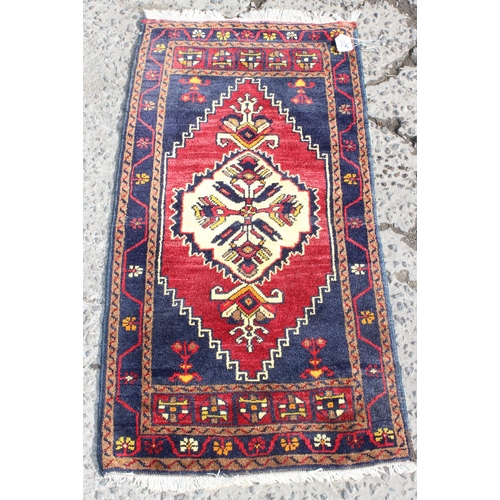 210 - A vintage red, blue and cream ground Turkish rug, approx 117cm x 55cm