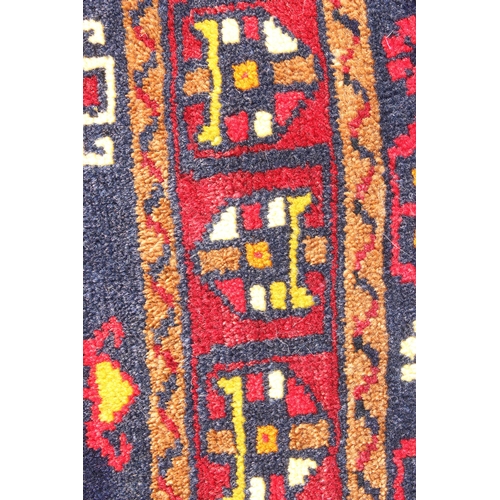 210 - A vintage red, blue and cream ground Turkish rug, approx 117cm x 55cm