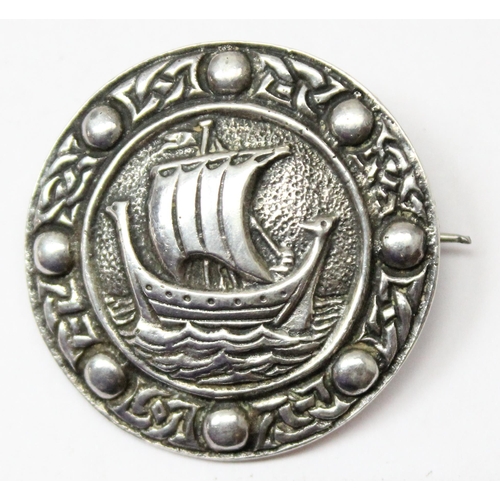 A retro Scottish silver brooch depicting a Viking ship within a Celtic